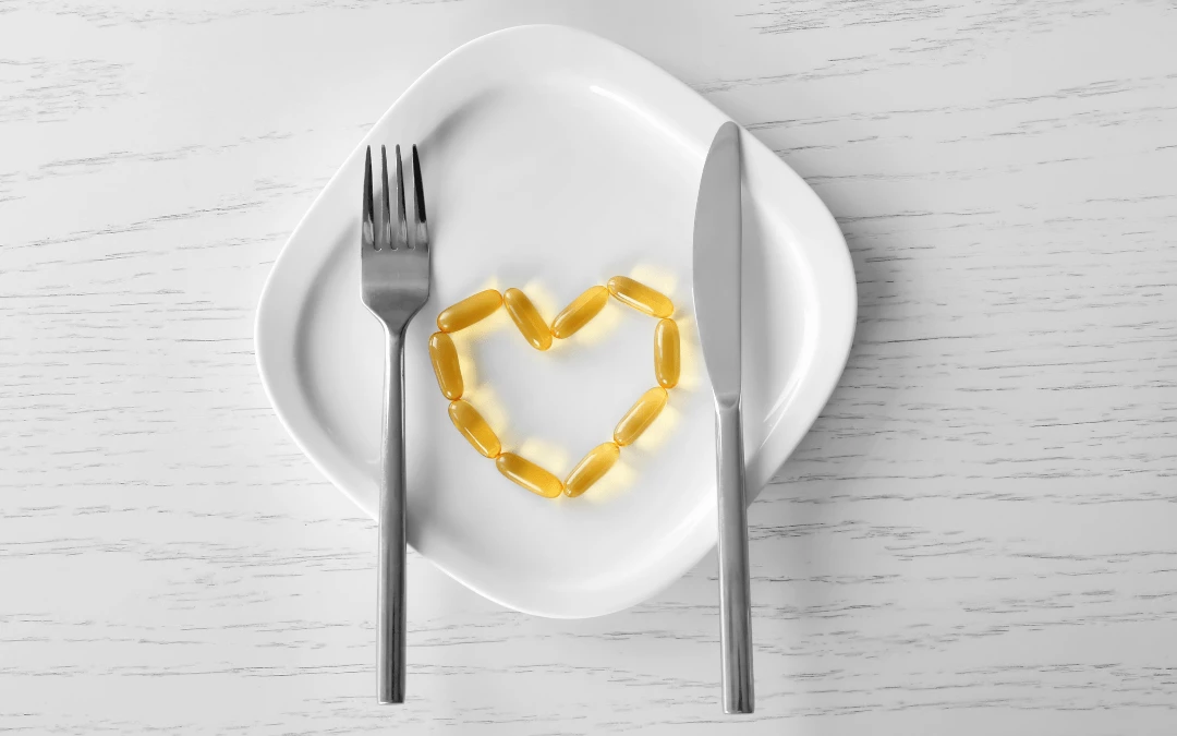 Fish Oil Capsules Arranged Into Heart Shape On A Plate With Fork And Spoon