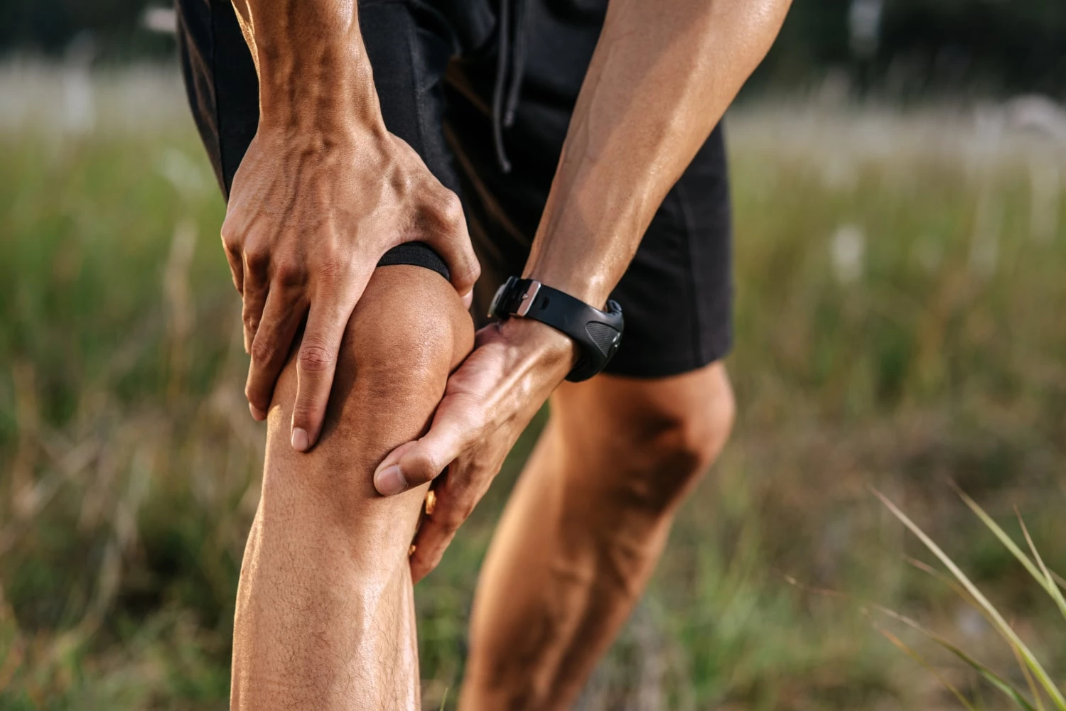 Man benting and grabbing his knee after exercising