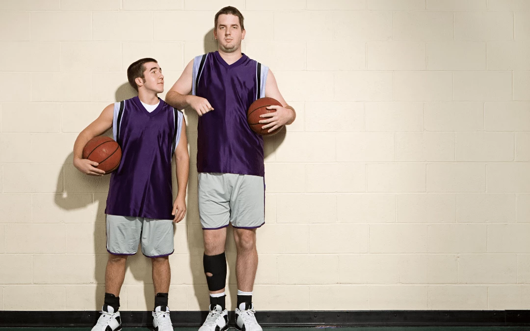 Short Man And Tall Man Holding Basketball Standing Side By Side Comparing Height