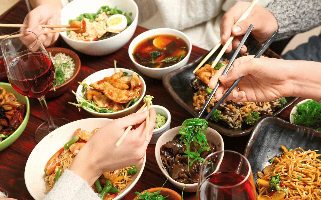 A Group Of Asian Hand Close Up Holding Chopstick And Sharing Dishes Together