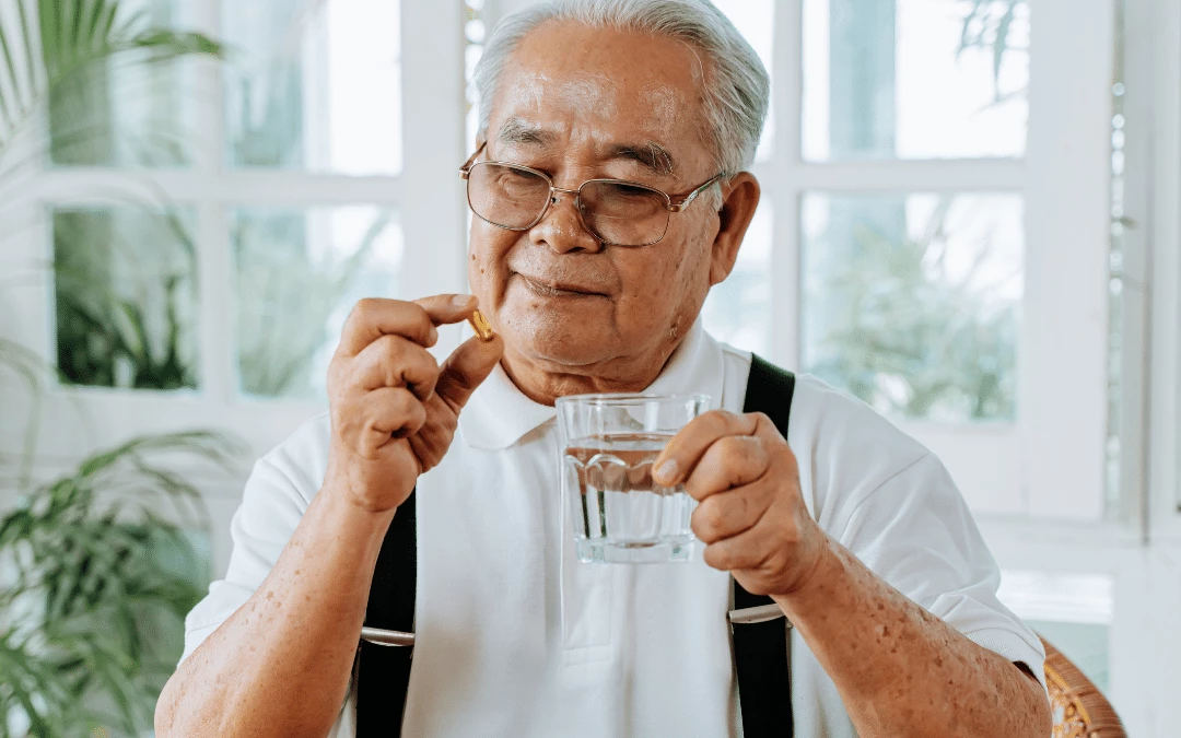 elderly-man-smiling-and-looking-at-a-medicine-pill-while-holding-a-glass-of-water-on-the-hand